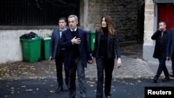 Бившият френски президент Никола Саркози поздравява свои привърженици, докато напуска дома си заедно със съпругата си Карла Бруни-Саркози в деня на влизането си в затвора „Санте“, за да започне петгодишна присъда.