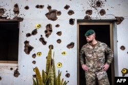 Военнослужащий армии Бельгии перед зданием со следами обстрела во время церемонии поминовения 10 бельгийских миротворцев, убитых во время гражданской войны в Руанде в 1994 году. Город Кигали, 8 апреля 2024 г.