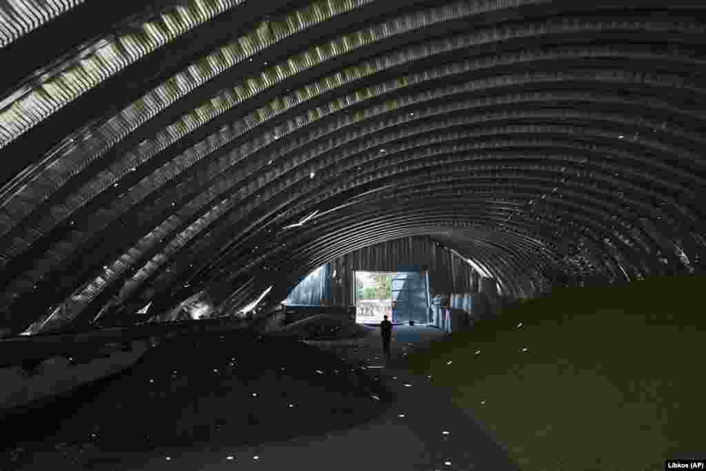A worker walks through a damaged farm storage structure.