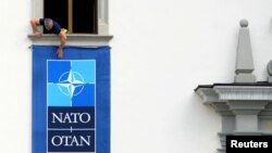 Работник монтира знамето на НАТО за срещата на върхана стената на Двореца на великите литовски князе във Вилнюс, Литва.