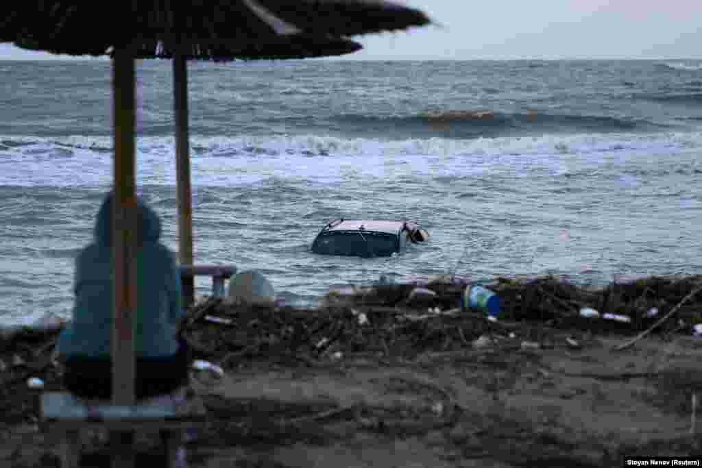 A woman looks at a car floating in the sea in the town of Tsarevo, on Bulgaria's Black Sea coast. on September 6. At least two men have died, and a search for a mother and child continues following torrential rains that caused widespread flooding in the region.