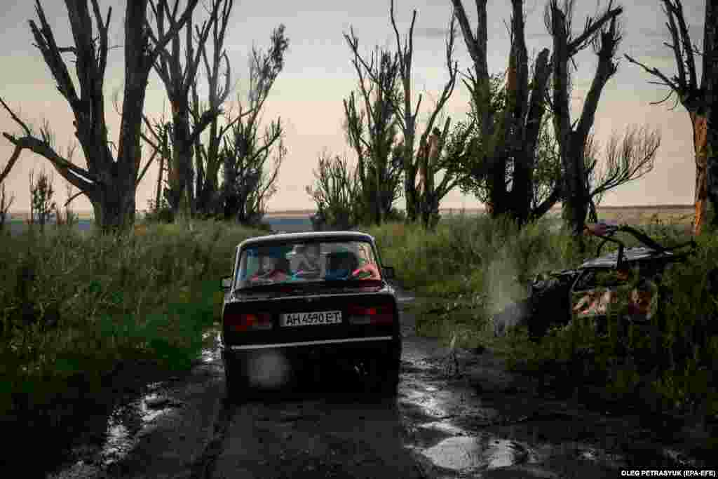 Mykola (41 ýaş) we onuň maşgalasy Ukrainanyň Harkow sebitiniň Dowhenke obasynda ulagly barýar, 2023-nji ýylyň 15-nji iýuly.&nbsp;Mykola Russiýanyň Ukrainada alyp barýan urşunyň dowamynda doganynyň zeper ýeten jaýynda abat galan zatlary ýygnamak üçin geldi. Söweş wagtynda onuň golaýdaky Krasnopillia obasyndaky öýi hem ýykyldy we ol maşgalasy bilen Hrestişe göçmäge mejbur boldy, ol ýerde ary saklaýar we bir gün öýüne dolanmagy umyt edýär. Rus goşunlary 2022-nji ýylyň 24-nji fewralynda Ukraina girip, weýrançylyga we gumanitar krizise sebäp boldy.(EPA-EFE/OLEG PETRASYUK)