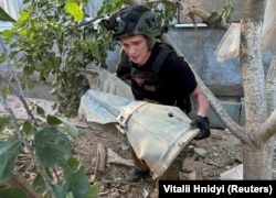 Un genist ucrainean transportă o parte dintr-o bombă rusească „cu planare” în apropierea unei case particulare lovite de un atac aerian rusesc în Harkov, în iunie.