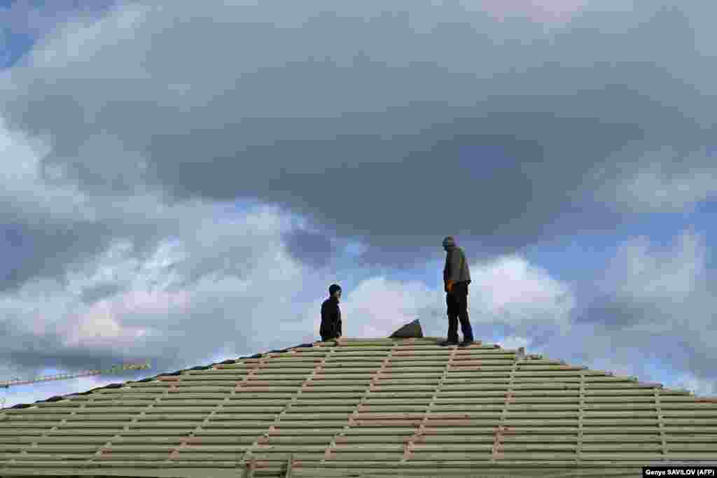 Muncitori construind noi case în locul celor distruse în timpul atacurilor rusești pe strada Vokzalna din Bucea, în apropiere de Kiev.