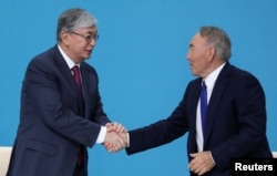 Президент Казахстана Касым-Жомарт Токаев пожимает руку бывшему президенту Нурсултану Назарбаеву на съезде правящей партии «Нур Отан» в Нур-Султане, Казахстан, 23 апреля 2019 года