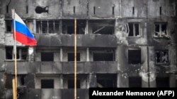 Руски флаг пред овъглено сдание в окупирания Мариупол. 