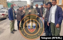 Recruți străini pentru un grup numit „Orchestra” pozează în Sankt Petersburg.