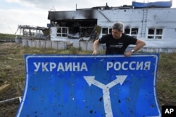 Генеральний директор Національного музею історії України у Другій світовій війні Юрій Савчук несе дорожній знак у місті Суджі. Курська область, Росія, серпень 2024