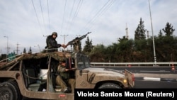 Израильские солдаты едут в военной машине недалеко от границы Израиля с сектором Газа, 11 октября 2023 года