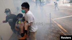 Полициянын чабуулунан качып, тилектешин куткарып бараткан демонстранттар. Гонконг. 24-май, 2020-жыл. 