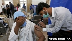 COVID-19га каршы вакцина алып жаткан киши. Пакистан. 2021-жылдын 10-марты. 
