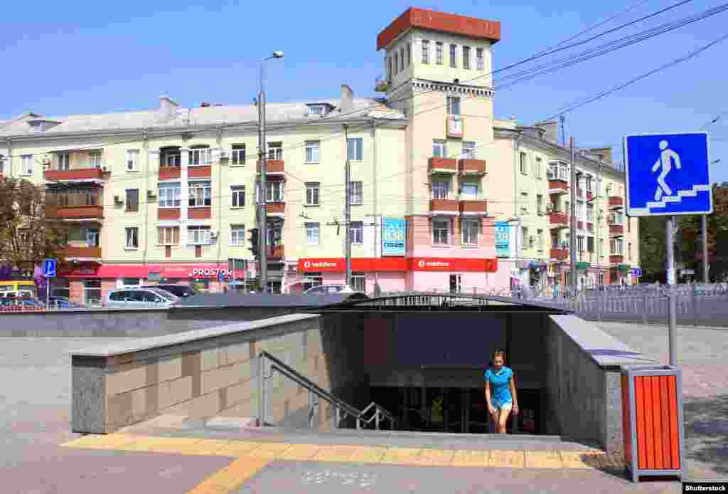 A woman emerges from an underpass at a crossroads in the center of Mariupol. Since this photo was taken in 2019, the building in background had a pyramid-shaped roof added to its turret.&nbsp;
