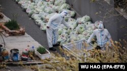 Медицинские работники готовят пакеты с едой для жителей многоквартирного дома, полностью заблокированных в квартирах из-за строгого карантина. Пекин, 28 ноября 2022 года