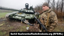 Донецк аймагында иштен чыккан орус танкынын жанында турган украин аскери.13-апрель, 2022-жыл.