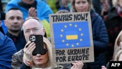 Участник демонстрации у Бранденбургских ворот в поддержку Украины держит плакат с надписью «Taurus now – for Ukraine, for Europe», 9 марта 2025 года, Берлин