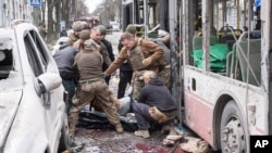 Мъже вадят тела на загинали от тролей, ударен от руска балистична ракета в Суми, 13 апри 2025 г.