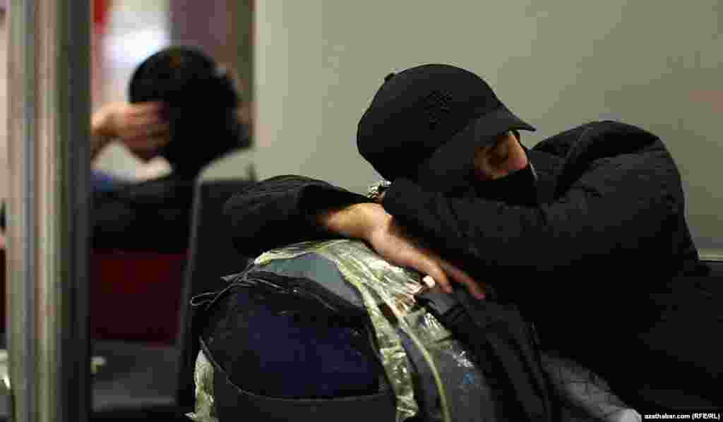 Uklap ýatan ýigidiň başyndaky papakda "Täze döwür" diýlen ýazgy bar.