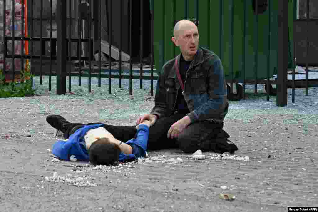 A man holds the hand of his 13-year-old son shortly after the boy was killed in a missile strike on Saltivka, Kharkiv, on July 20. The district of the eastern Ukrainian city has been heavily bombarded since the opening of the Russian invasion and is now largely deserted.&nbsp;