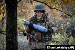 Soldat ucrainean cărând un obuz cu un mesaj pentru armata rusă, pe linia frontului de lângă Bahmut, 27 octombrie 2022.