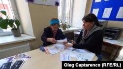 O femei este ajutată de asistenta socială să se înregistreze pentru a putea beneficia de compensație pentru perioada de iarnă. Fotografie din 2022. 