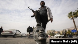 СИРИЯ – Боец оппозиции наступает на сломанный бюст покойного президента Сирии Хафеза Асада в Дамаске, Сирия,  8 декабря 2024 г.