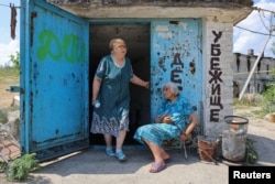 Местные жительницы у входа в бомбоубежище, находящемся на территории стекольной фабрики в Лисичанске на востоке Украины (фото сделано в июле 2022 года)