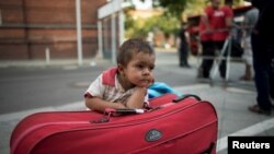 Ребенок мигрантов ожидает своих родителей у канцелярии по делам здравоохранения и социальным вопросам. Берлин, 10 августа 2015 года.