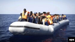 Нелегальных мигрантов из Африки перевозят на спасательных лодках итальянских ВМС после крушения корабля, на котором они находились. Средиземное море, сентябрь 2014 года.  
