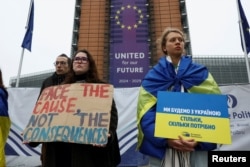 Люди тримають банери під час демонстрації біля будівлі, де працює Європейська комісія, на підтримку використання заморожених російських активів для фінансування України, Брюссель, Бельгія, 17 грудня 2025 року