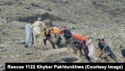 په کوهستان کې مرستندویه کارکوونکي او ځايي خلک د ټرافیکي پېښې ښکار شوی کس امبولانس ته انتقالوي - د مې لومړۍ نېټې انځور. 