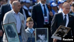 Russian President Vladimir Putin (right) holds a portrait of his father as he takes part in the Immortal Regiment march in Moscow on May 9.