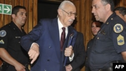 Бывший президент Аргентины Хорхе Рафаэль Видела разговаривает с полицейским перед судом. Декабрь 2010 года.  