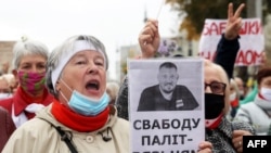 Минскидеги акцияда Сергей Тихановскийдин сүрөтүн көтөрүп турган пенсионер.  2020-жыл