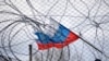 Руско знаме се развява зад ограда и бодлива тел.