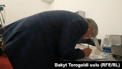 Конституциялык кеңешменин мүчөсү долбоорго кол коюп жатат. 27-январь, 2020-жыл.