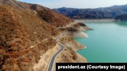 A newly built highway that winds past a water reservoir in the Aghdara region, photographed in March 2025.