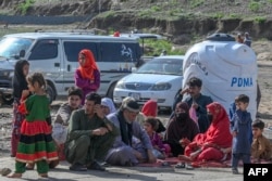 په لواړګي کې یوه افغانه کورنۍ هېواد ته تر ستنېدو مخکې د نوملیکنې له مرکز سره انتظار باسي - د اپرېل ۱۹مې انځور.