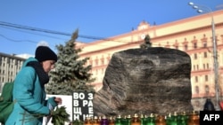 Женщина возлагает цветы и свечу на акции памяти у Соловецкого камня. Москва, 29 октября 2014 года.