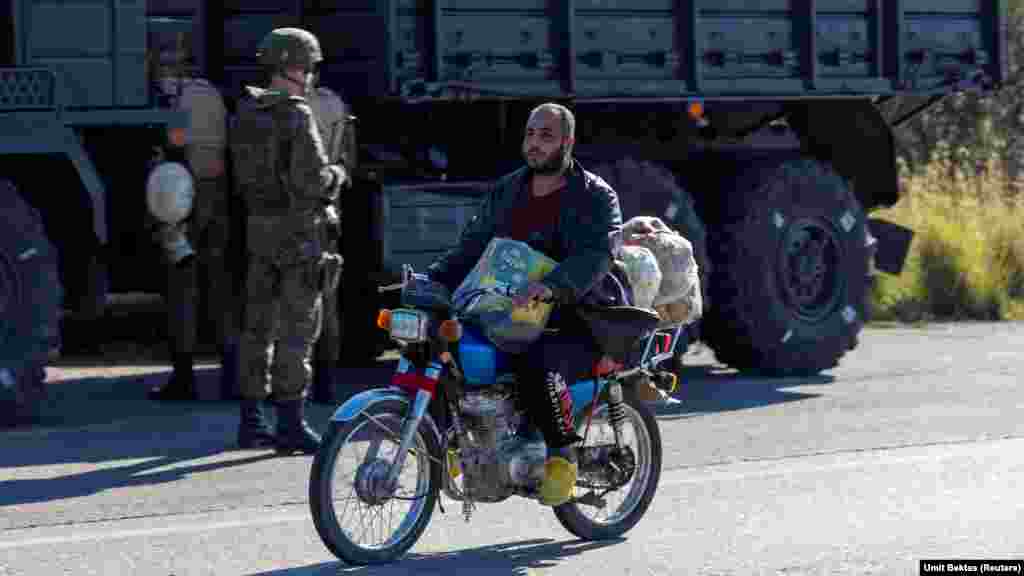 Mještanin prolazi pored ruskog konvoja u blizini vazdušne baze Hmeimim. "Lokalno stanovništvo samo gleda", kaže Bektas o situaciji oko baze, koja je sada bez vanjske vojne zaštite duž svog perimetra. "U selu u blizini vazdušne baze ima mnogo trgovina s natpisima na ruskom jeziku", kaže Bektas, ali sve su sada zatvorene. "Nema ruskih vojnika koji izlaze pojedinačno ili u neoklopnim vozilima ili bilo što slično." &nbsp;