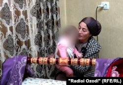 Максуда Шаропова, мать Рухшоны, укладывает маленькую внучку в колыбель