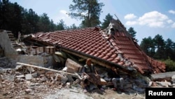 A Bulgarian Romany woman sits in front of her house after it was demolished in a Romany suburb of the city of Stara Zagora in July 2014.
