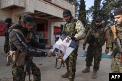 Luptători militanți sirieni incendiază o fotografie a președintelui sirian destituit Bashar al-Assad în Alep pe 29 noiembrie 2024.