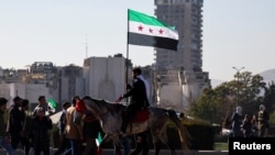 Syria - A man holding a flag adopted by Syria's new rulers rides a horse, after Syria's Bashar al-Assad was ousted, in central Damascus, December 15, 2024. 