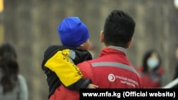 Қизил ярим ой жамияти вакили Ироқдан олиб келинган болани кўтариб турибди. Архив