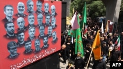 Mourners walk by a poster bearing the portraits of scientists and military commanders killed during the 12-day war between Iran and Israel, in Tehran on July 5.