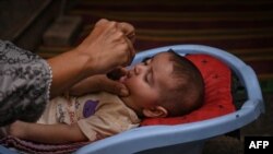 په کراچۍ کې یوه روغتیايي کارکوونکی يو ماشوم ته د ګوزڼ واکسیني څاڅکي ورکوي - انځور له ارشیفه.