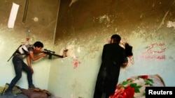 "Эркин Сирия" армиясынын жоокерлери тешиктен ок атууда. Алеппо шаарынын Карм ал-Жабал району. 23-июль, 2013