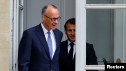 French President Emmanuel Macron walks with Germany's newly elected chancellor, Friedrich Merz, at the Elysee presidential palace in Paris on May 7.