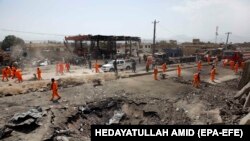 Civili care inspectează locul unde a fost distrusă benzinăria, în urma atacului cu bombă de la Kabul, din Zona Verde