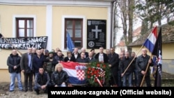 Spomen-ploča i članovi Udruge dragovoljaca Hrvatskih obrambenih snaga ispred ploče sa pozdravom "Za dom spremni" postavljene u Jasenovcu 5. decembra 2016.